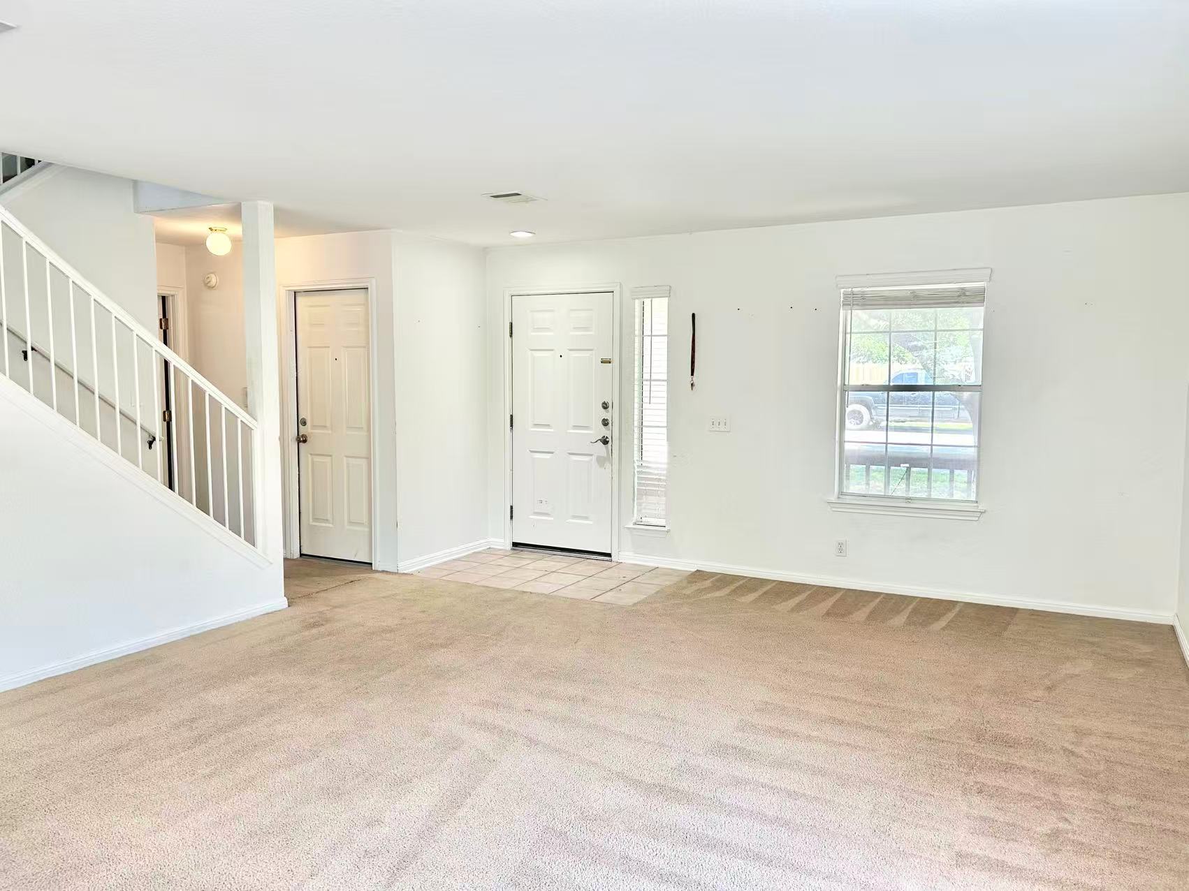 5608 Netleaf Road Austin, TX 78724 - Photo 5 of 26 A well-lit living area features carpeted flooring, a front entry, and a staircase.