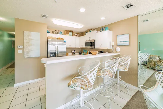 a kitchen with stainless steel appliances a sink a stove a refrigerator cabinets and a dining table