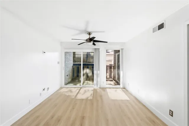a view of a room with wooden floor ceiling fan and window