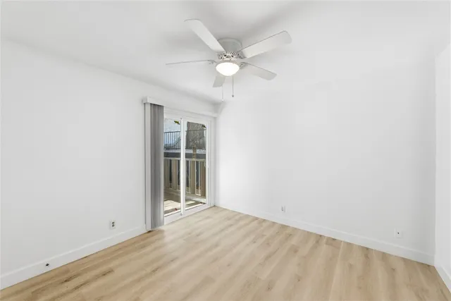 an empty room with a ceiling fan and window