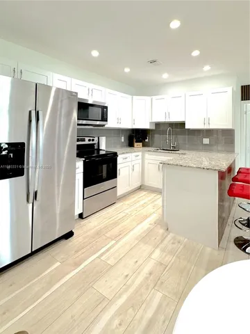 a kitchen with stainless steel appliances granite countertop a refrigerator sink and microwave