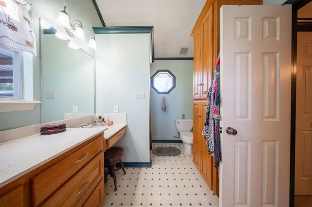 a bathroom with a granite countertop sink mirror vanity and toilet