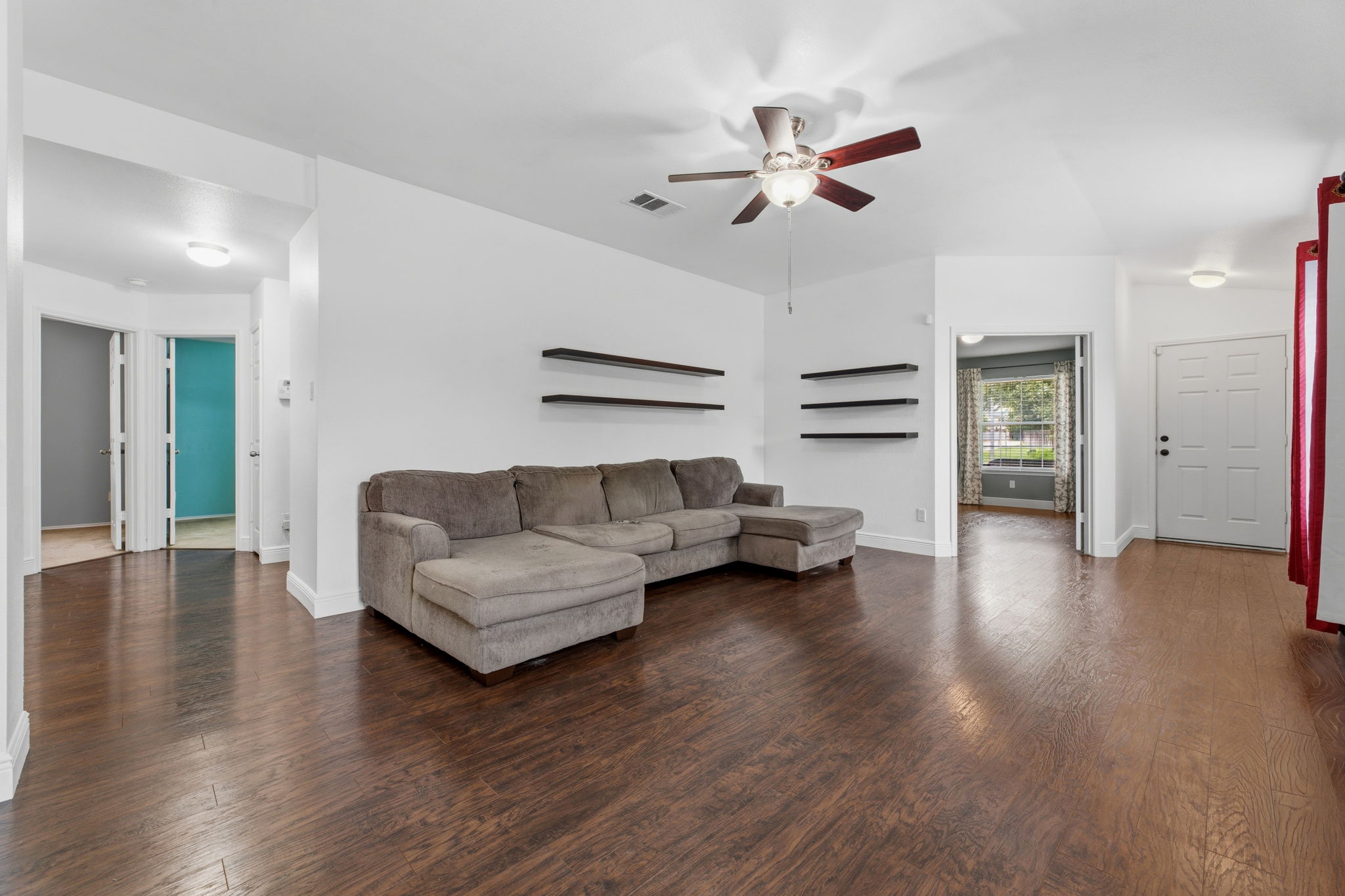 12601 Waynespur Lane Elgin, TX 78621 - Photo 9 of 38 Rich hardwood flooring stretches across this comfortable living room, illuminated by a ceiling fan.