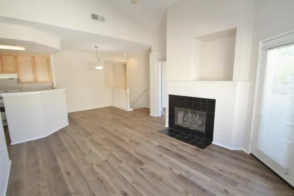 an empty room with wooden floor fireplace and windows