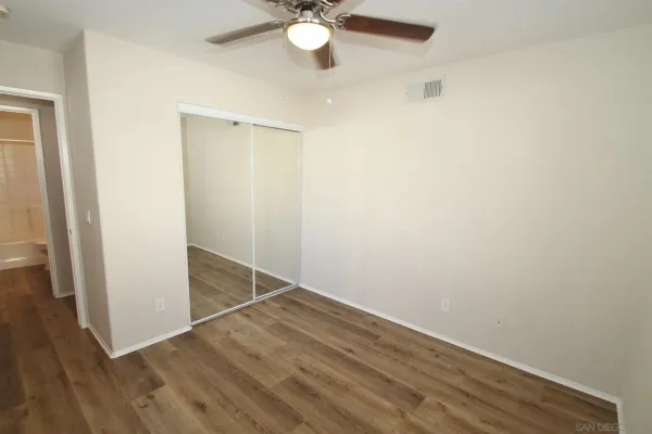 an empty room with wooden floor and fan