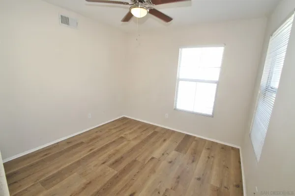 an empty room with a window and a fan