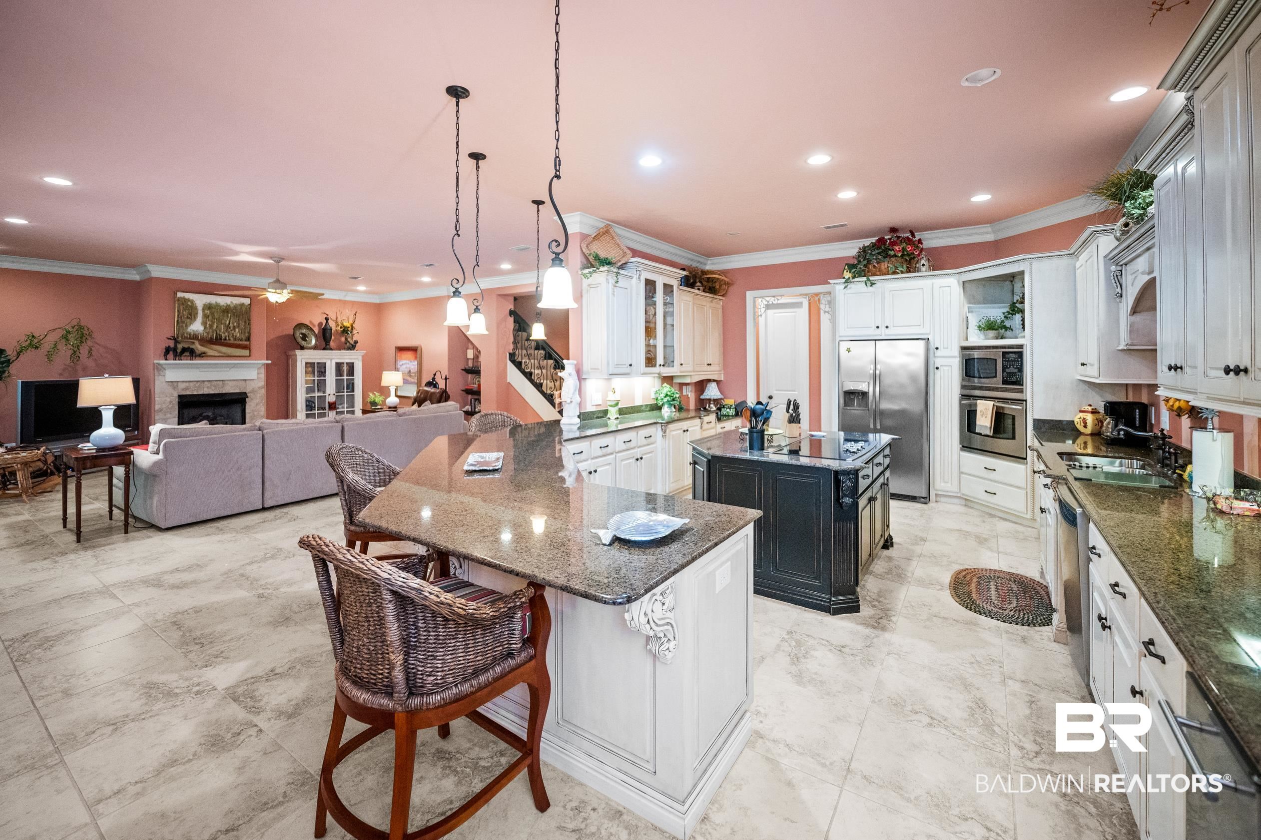 404 Peninsula Boulevard Gulf Shores, AL 36542 - Photo 6 of 51 Kitchen featuring a breakfast bar, dark stone counters, white cabinetry, a tile fireplace, and ornamental molding
