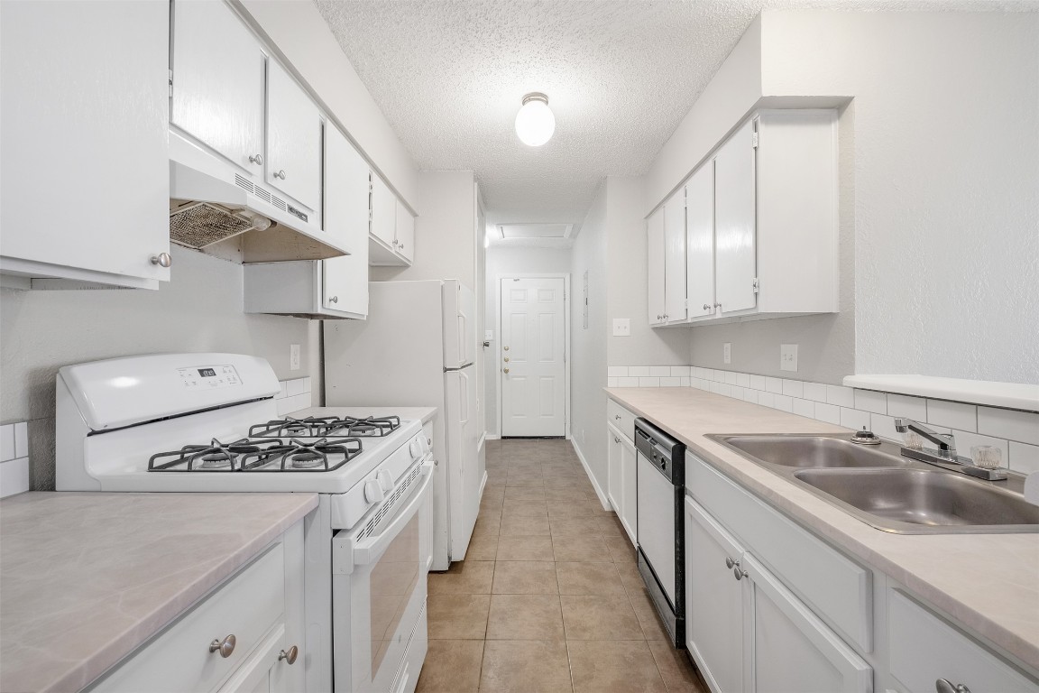 12901 Chromite Street, Unit B Austin, TX 78727 - Photo 1 of 21 Kitchen featuring white gas range, light countertops, white cabinetry, dishwashing machine, and a textured ceiling