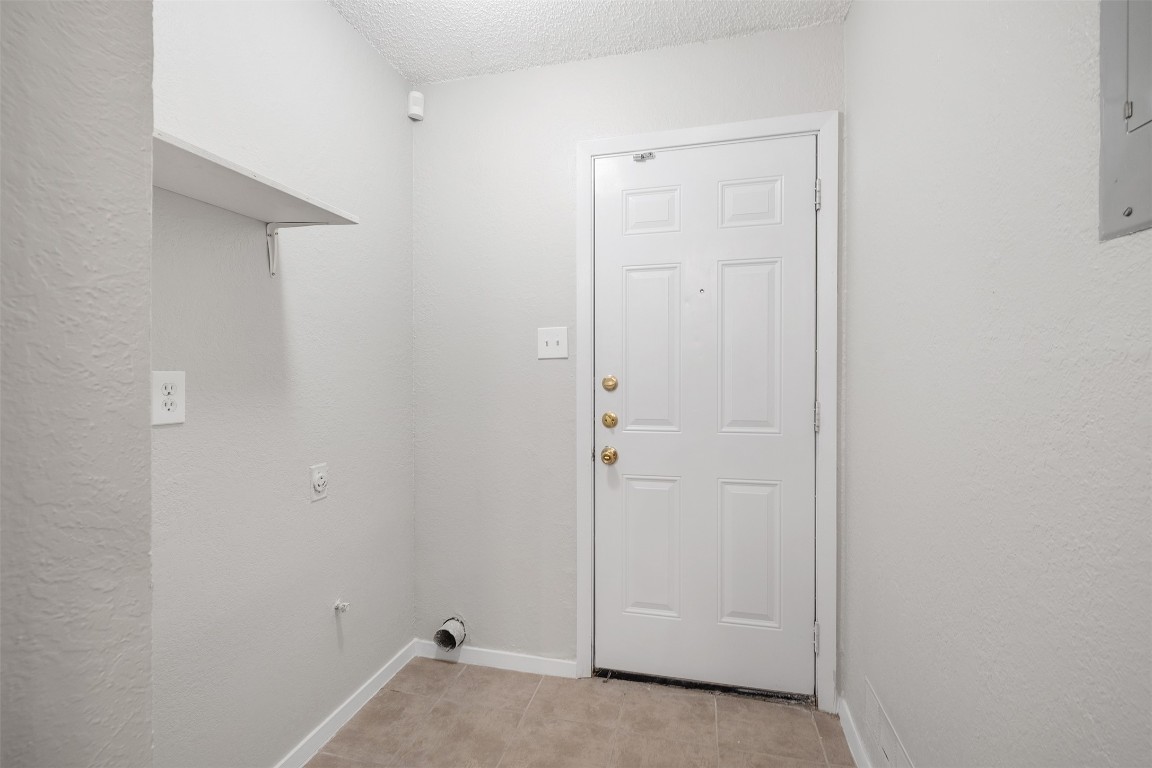 12901 Chromite Street, Unit B Austin, TX 78727 - Photo 15 of 21 Laundry area featuring a textured ceiling, light tile patterned floors, and electric panel
