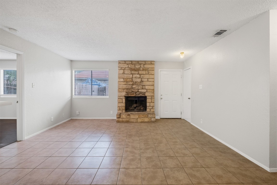 12901 Chromite Street, Unit B Austin, TX 78727 - Photo 3 of 21 Unfurnished living room featuring a textured ceiling, a fireplace, and light tile patterned floors