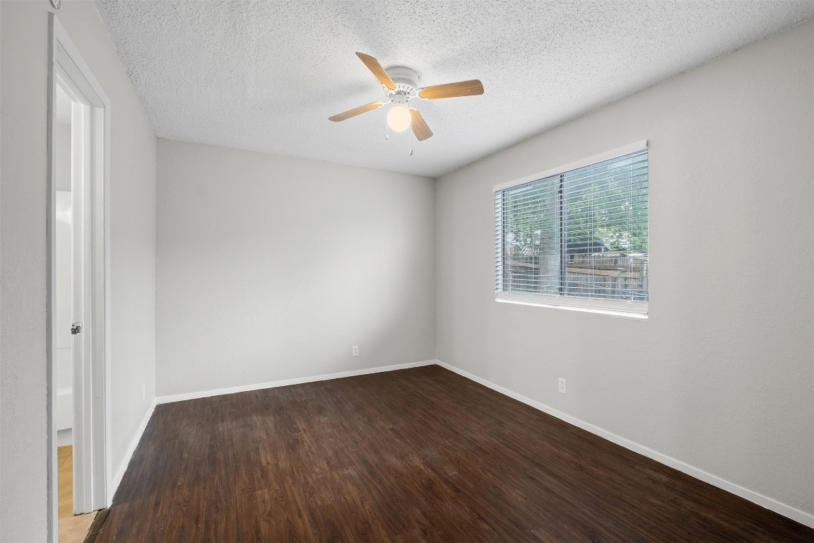 12901 Chromite Street, Unit B Austin, TX 78727 - Photo 5 of 21 Empty room featuring dark wood-style floors, a ceiling fan, and a textured ceiling