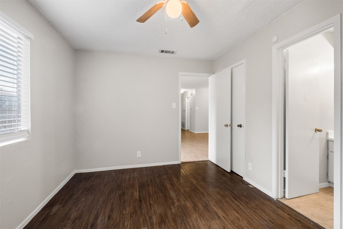 12901 Chromite Street, Unit B Austin, TX 78727 - Photo 6 of 21 Unfurnished bedroom with dark wood-style flooring, a textured ceiling, ceiling fan, and ensuite bath