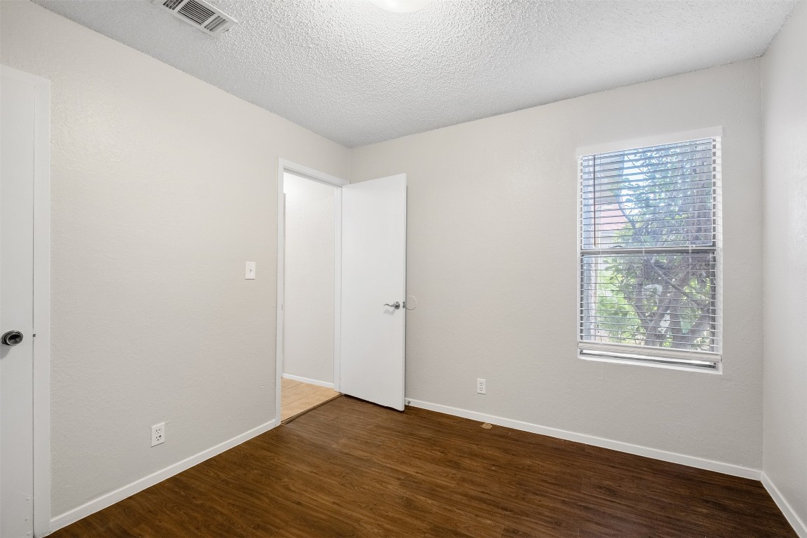 12901 Chromite Street, Unit B Austin, TX 78727 - Photo 10 of 21 Spare room featuring dark wood-style flooring and a textured ceiling