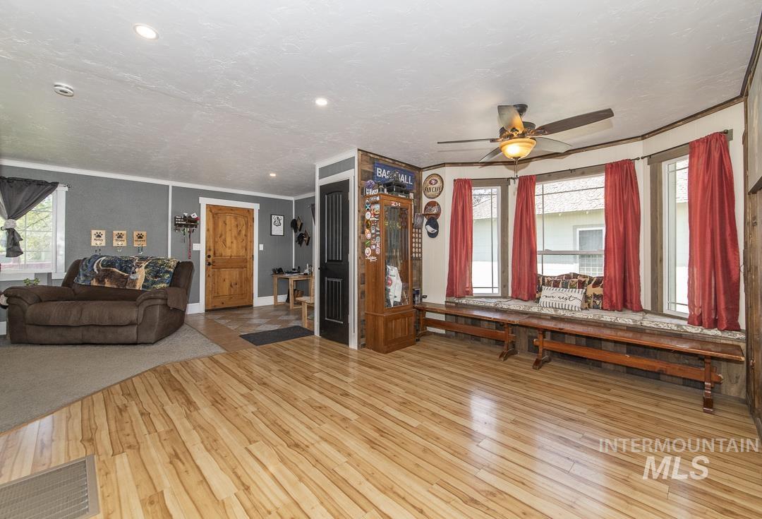 486 West Main Street South Vale, OR 97918 - Photo 11 of 37 Spacious living area featuring wood-finish flooring, a bay window with a built-in bench, ceiling fan with integrated lighting, recessed lighting, and a paneled wood entry door