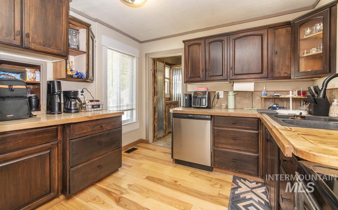 486 West Main Street South Vale, OR 97918 - Photo 13 of 37 Kitchen featuring light wood-finish flooring, wood cabinetry with dark finish, light-toned countertops, and a stainless steel dishwasher
