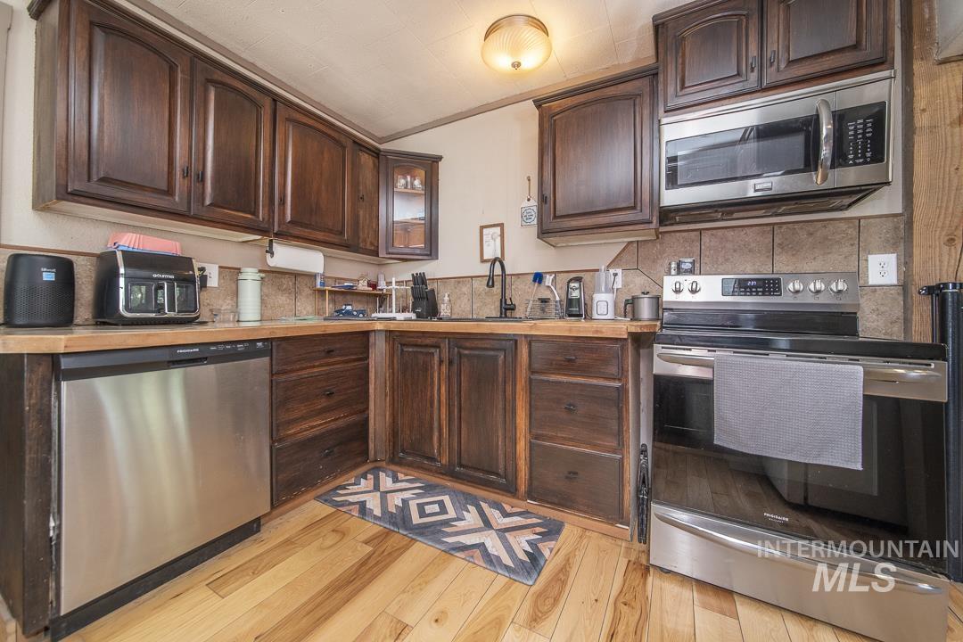 486 West Main Street South Vale, OR 97918 - Photo 14 of 37 Kitchen featuring wood cabinetry, natural wood-finish countertops, stainless steel appliances, tile backsplash, and light wood-finish flooring
