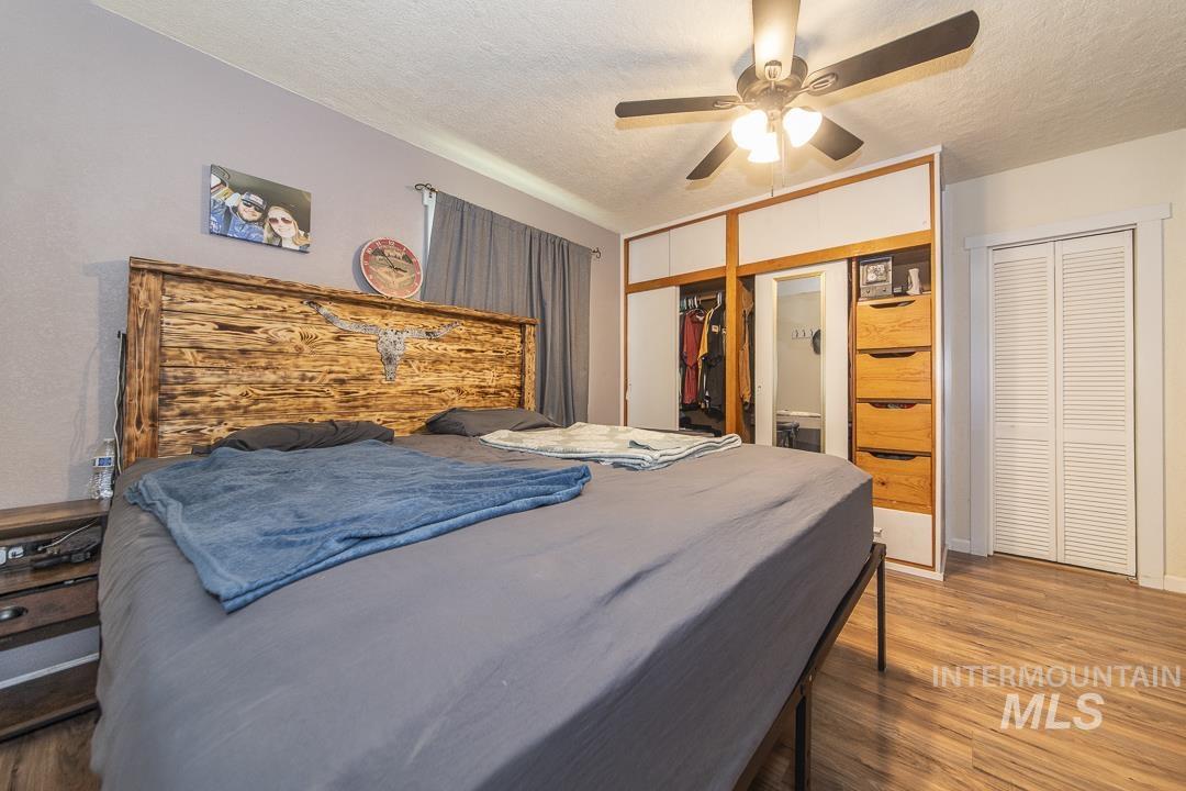 486 West Main Street South Vale, OR 97918 - Photo 21 of 37 Bedroom featuring wood-finish flooring, a ceiling fan with integrated lighting, and a built-in wardrobe with sliding doors, a mirrored panel, and integrated drawers