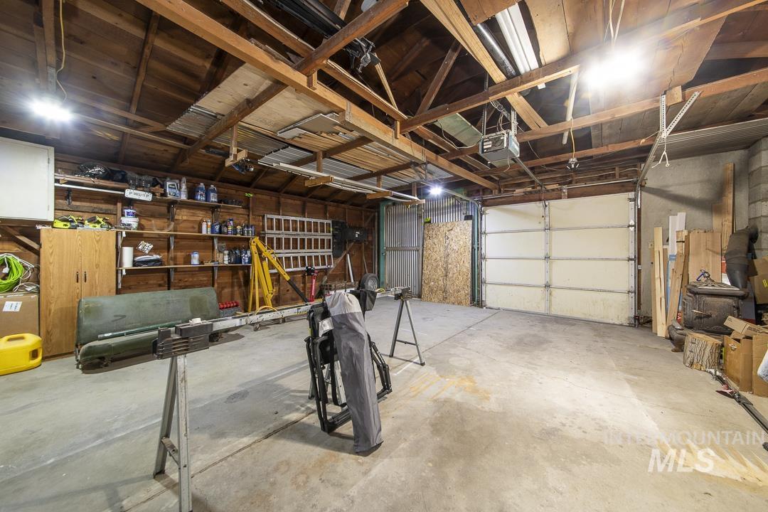 486 West Main Street South Vale, OR 97918 - Photo 29 of 37 Spacious garage featuring exposed wood ceiling beams, concrete flooring, built-in wall shelving, and an overhead door