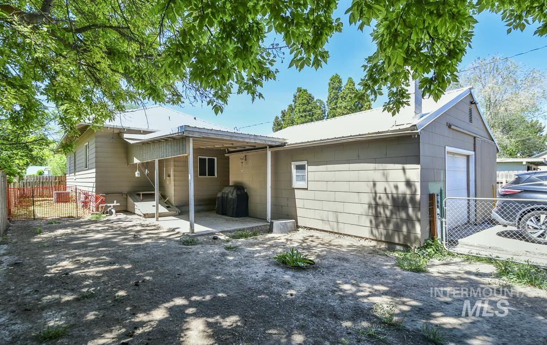 486 West Main Street South Vale, OR 97918 - Photo 35 of 37 Rear exterior featuring a covered concrete patio, an attached garage with a roll-up door, and a partially fenced yard