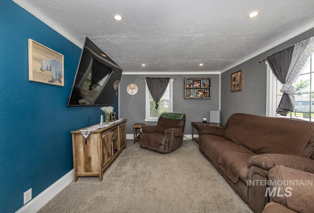486 West Main Street South Vale, OR 97918 - Photo 8 of 37 Living room with textured blue accent wall, recessed ceiling lighting, textured gray walls, white crown molding, and light-toned carpet flooring