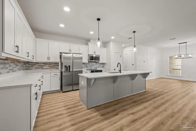 a kitchen with kitchen island granite countertop a sink cabinets and wooden floor