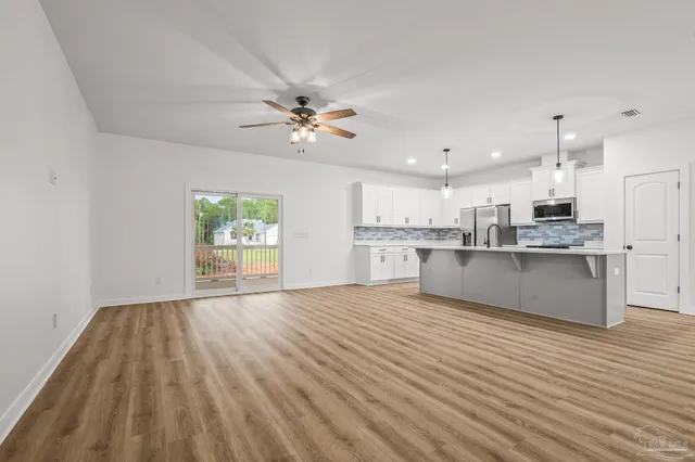 a kitchen with stainless steel appliances granite countertop a sink a stove a refrigerator and white cabinets with wooden floor