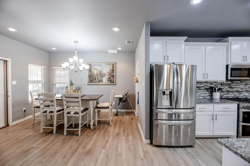 7101 22nd Place Lubbock, TX 79407 - Photo 7 of 24 a kitchen with stainless steel appliances a dining table chairs stove refrigerator and cabinets