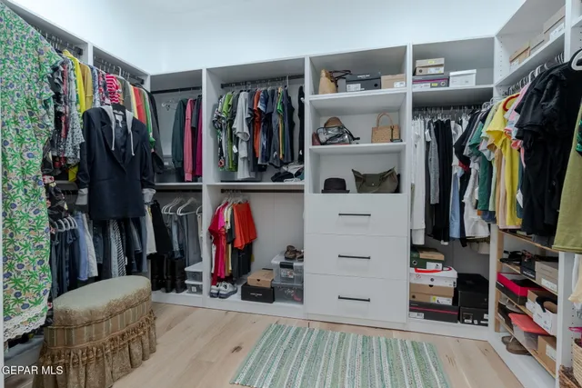 a view of walk in closet with clothes and shoes