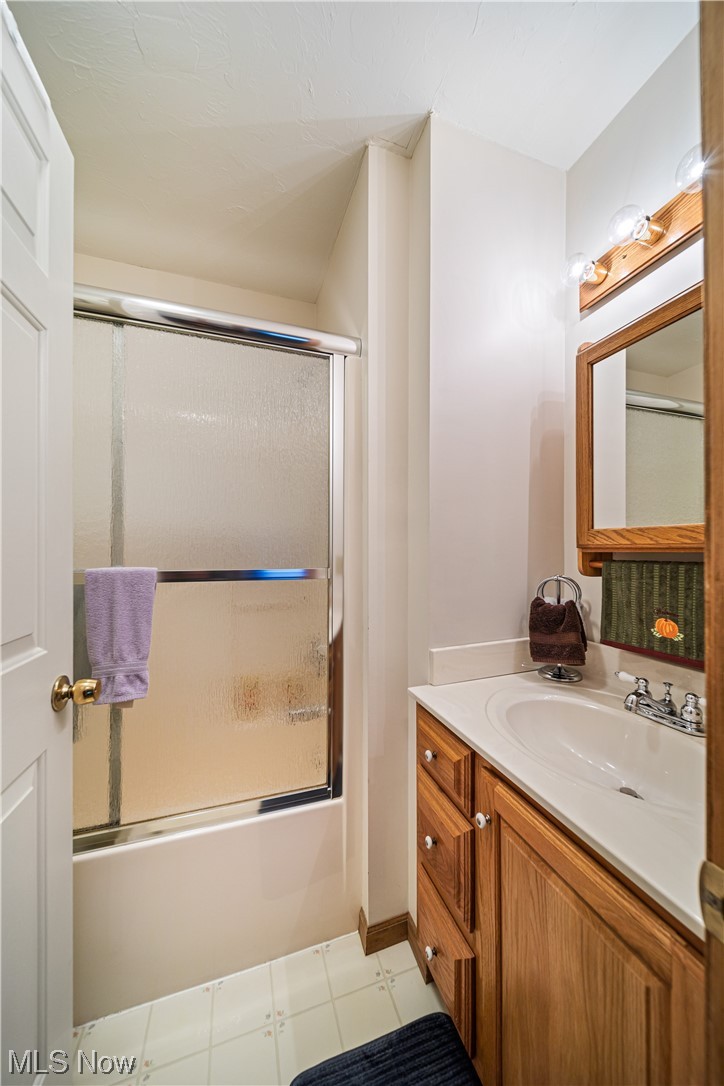 431 Ansel Road Geneva, OH 44041 - Photo 25 of 35 Bathroom with vanity, mirror, bath / shower combo with glass door, and light tile floors