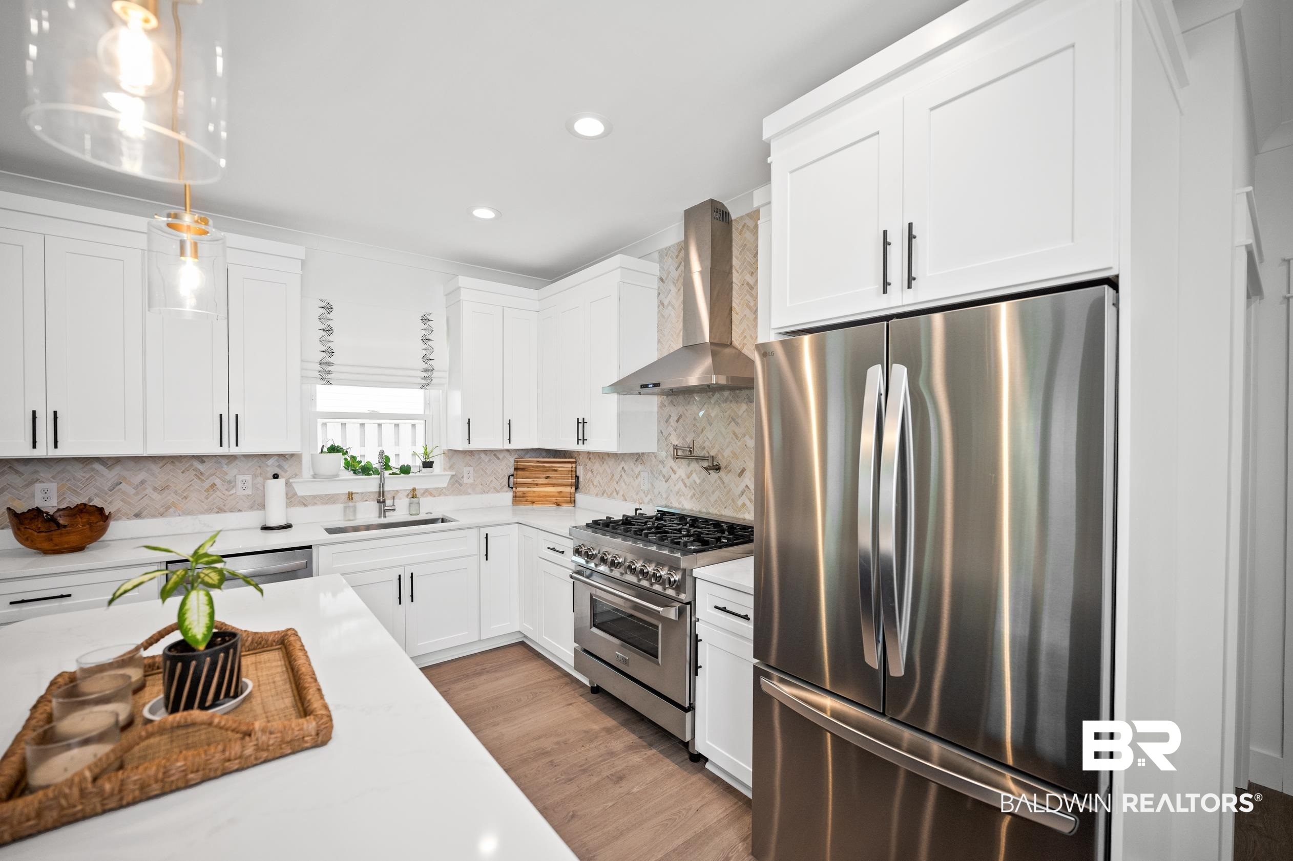 5501 Mobile Avenue Orange Beach, AL 36561 - Photo 9 of 40 Kitchen featuring stainless steel appliances, wall chimney exhaust hood, recessed lighting, white cabinetry, and backsplash