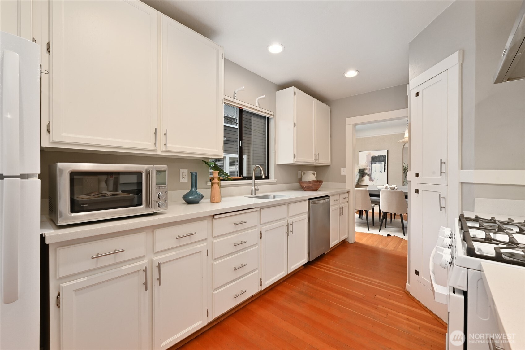 6056 25th Avenue Northeast Seattle, WA 98115 - Photo 13 of 34 a kitchen with stainless steel appliances granite countertop a stove a sink and white cabinets with wooden floor
