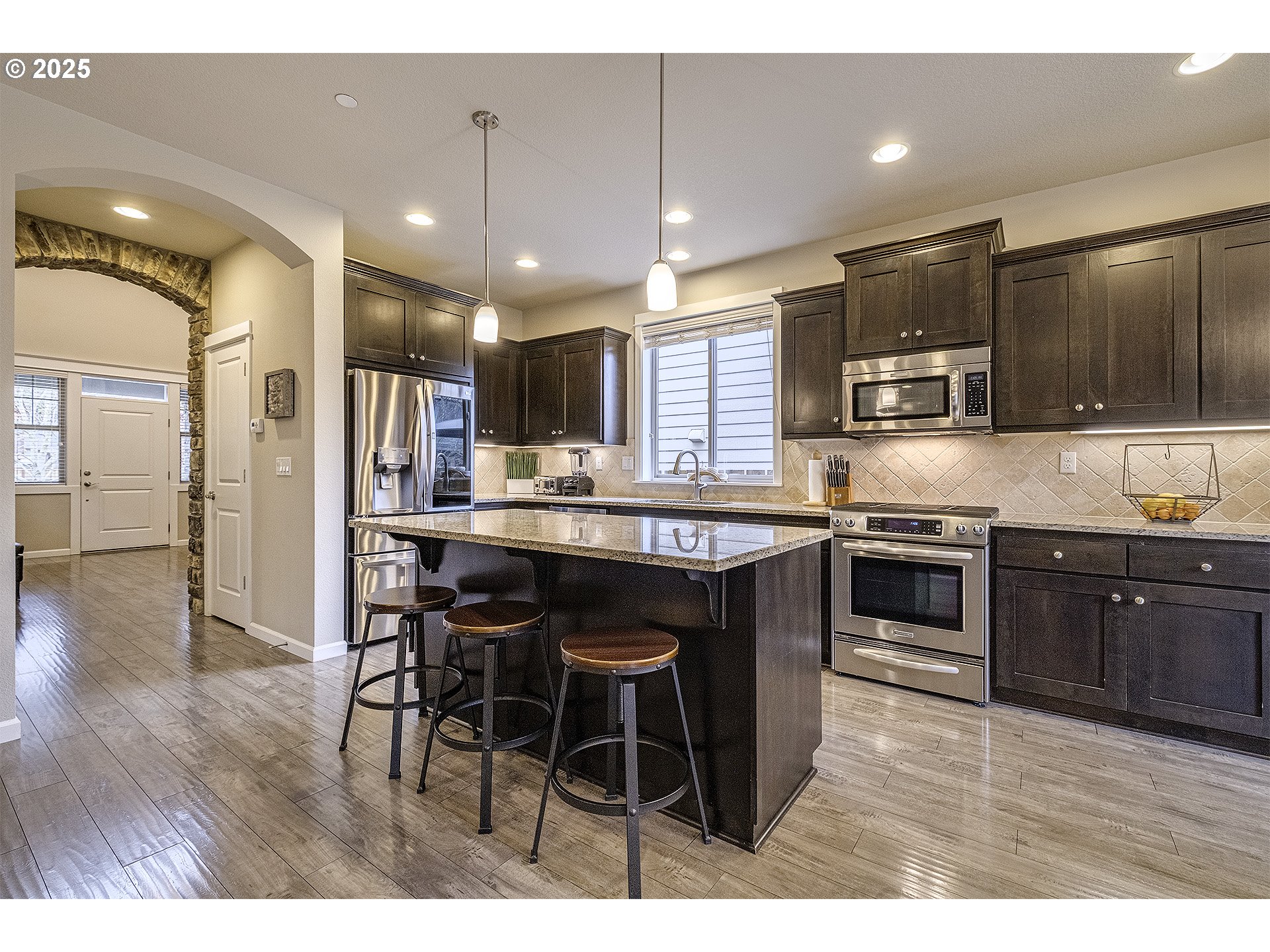 22831 Southwest Park Row Sherwood, OR 97140 - Photo 6 of 33 a kitchen with stainless steel appliances kitchen island granite countertop a sink a stove a microwave a counter top space and cabinets