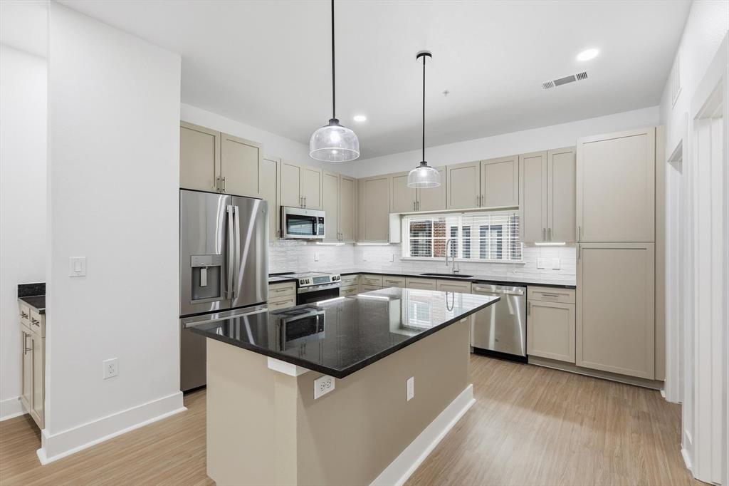 4110 Fairmount Street, Unit 1003 Dallas, TX 75219 - Photo 12 of 35 a kitchen with kitchen island a sink appliances a counter space and a window