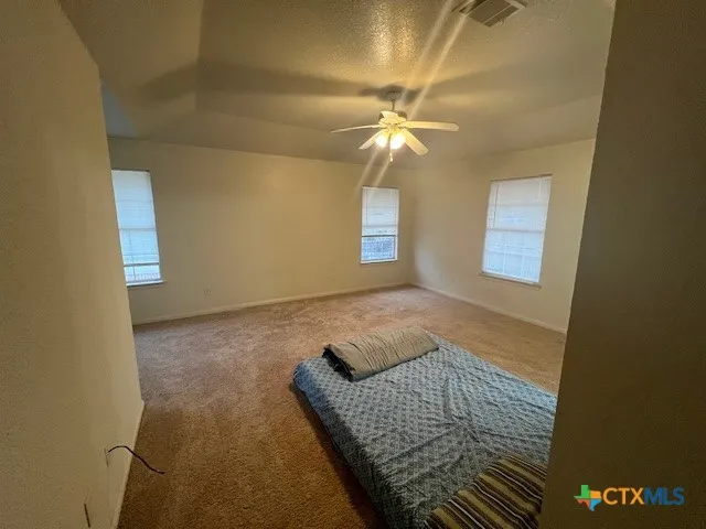 an empty room with a chandelier fan and a window