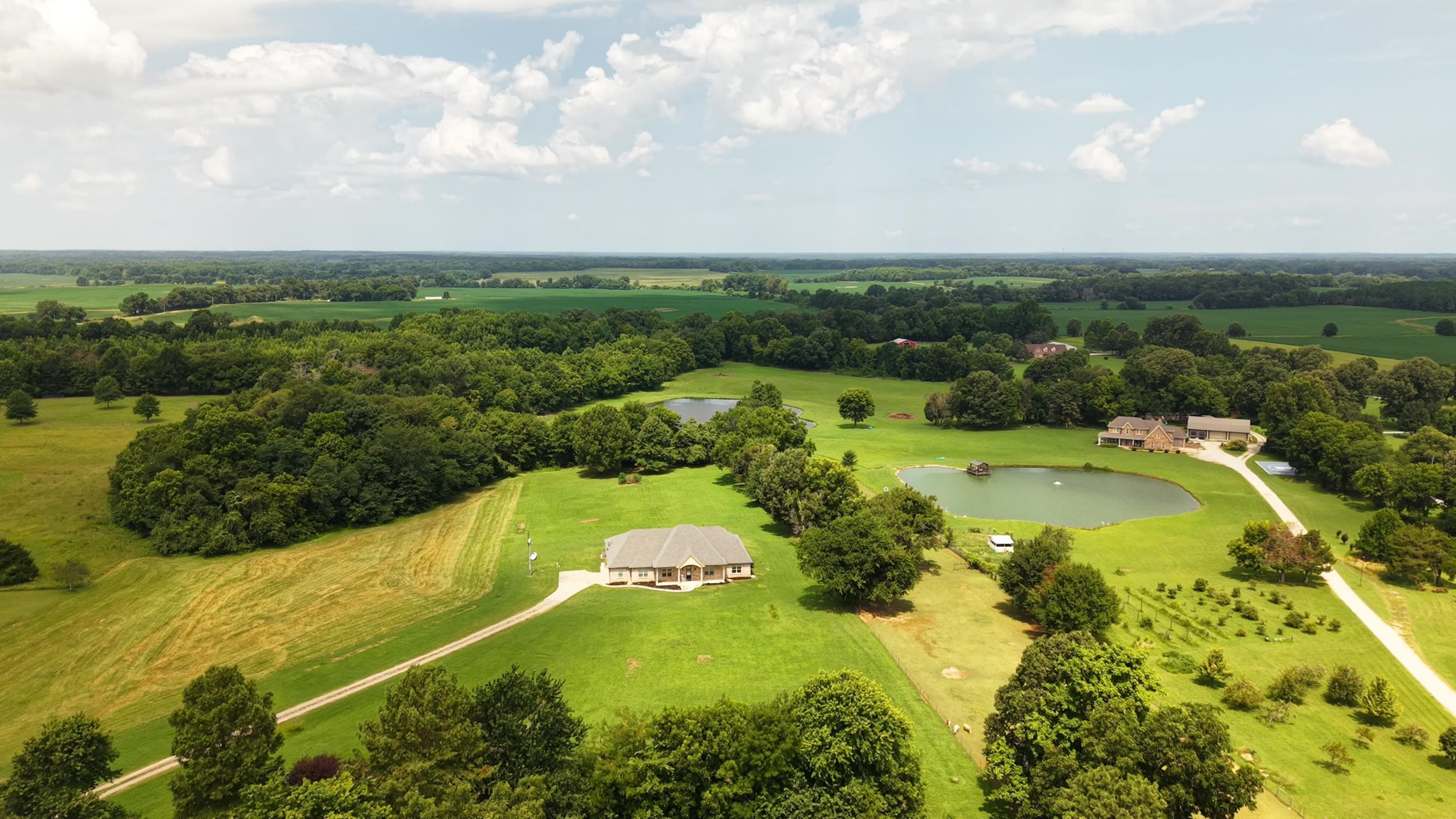 185 Belmont Road Mason, TN 38049 - Photo 3 of 38 Expansive rural property featuring two residential structures, extensive green spaces, mature trees, and two distinct ponds