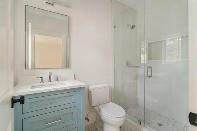 a bathroom with a toilet sink vanity and shower