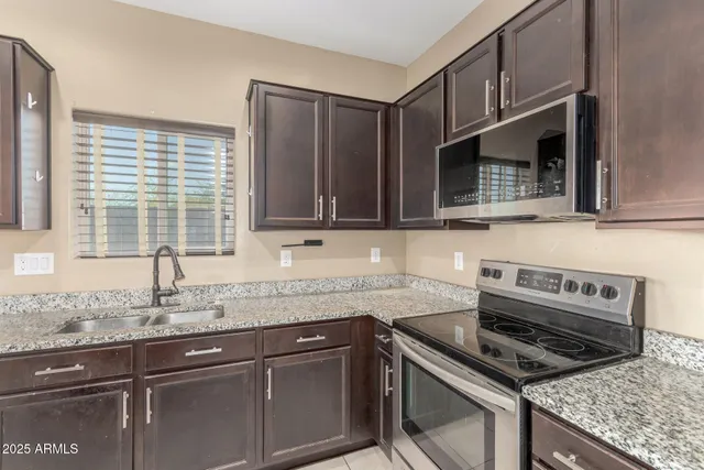 a kitchen with granite countertop a sink stove top oven and microwave