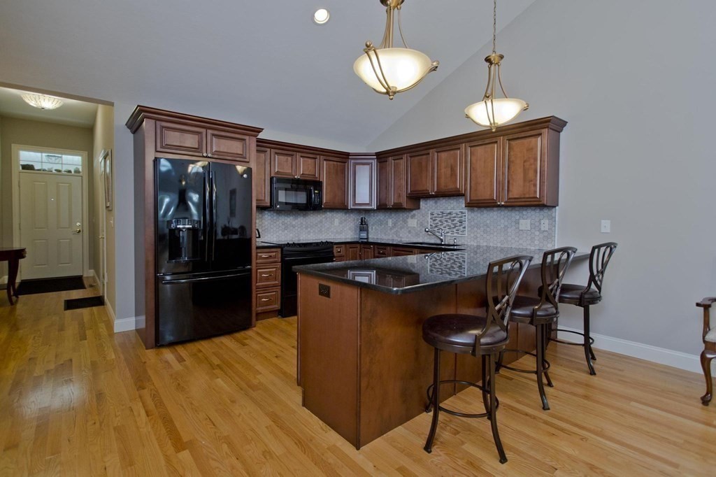 73 Beech Hill Road, Unit 73 West Springfield, MA 01089 - Photo 5 of 29 a kitchen with stainless steel appliances granite countertop a stove a refrigerator a sink a dining table and chairs with wooden floor