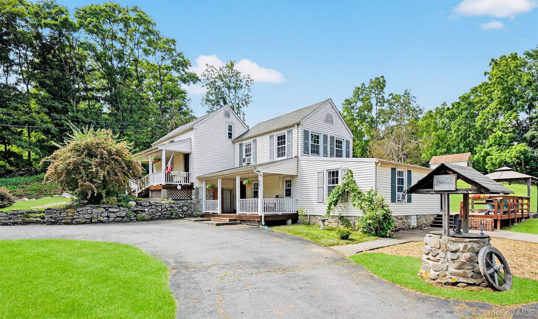 a view of a white house with a big yard and potted plants