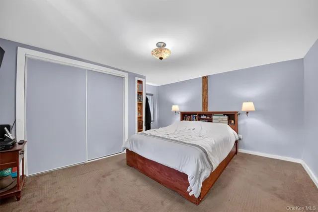 a bedroom with a bed wall painting and a lamp on the dresser