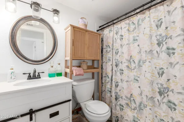 a bathroom with a toilet a sink a mirror a window and a shower curtain