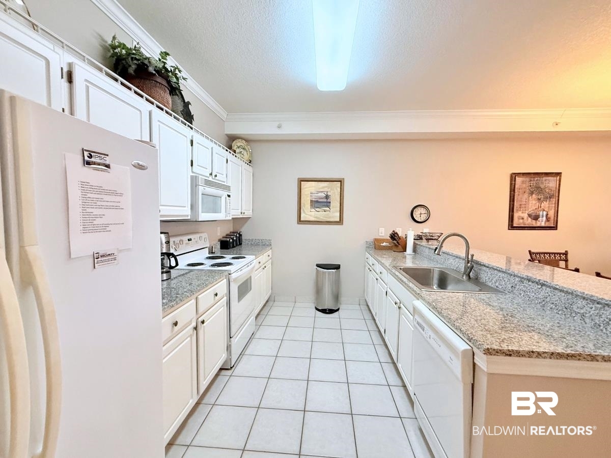 27284 Gulf Road, Unit 212 Orange Beach, AL 36561 - Photo 9 of 35 Kitchen featuring white appliances, a peninsula, white cabinets, crown molding, and a textured ceiling