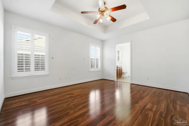 a view of empty room with wooden floor and fan