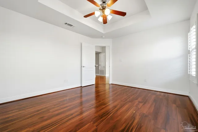 a view of an empty room with window and wooden floor