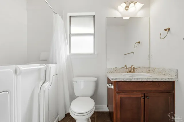 a bathroom with a granite countertop toilet sink and mirror