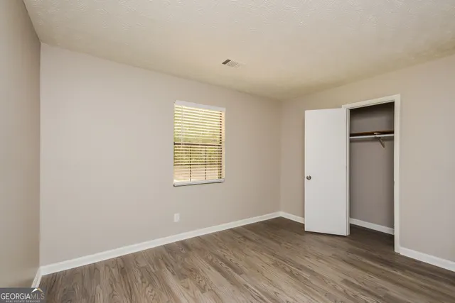 an empty room with wooden floor and windows