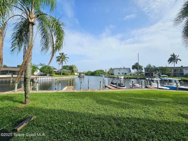 a view of a house with a big yard and palm trees