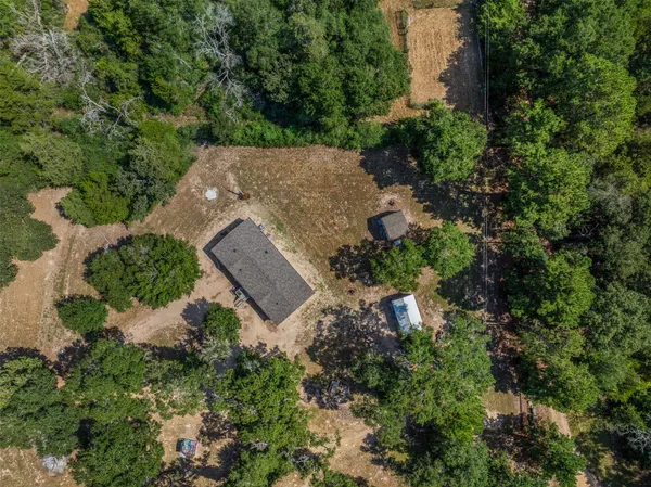 an aerial view of a house with a yard and trees all around