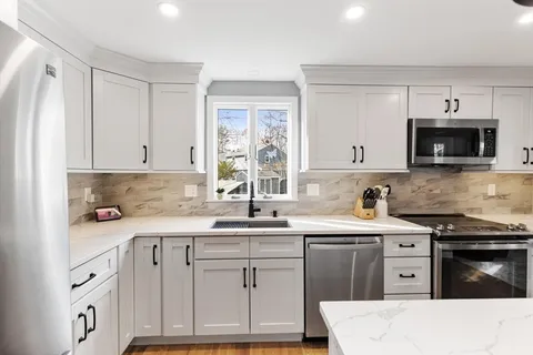 a kitchen with stainless steel appliances a sink a stove a table and chairs