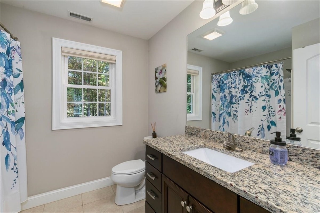 135 Pepperell Road Groton, MA 01450 - Photo 24 of 41 a bathroom with a granite countertop sink a toilet and a window